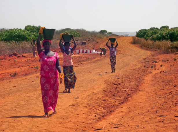 Click to view full size Senegalese women in Keur Moussa transport rocks to construct a dike to control soil erosion in their community