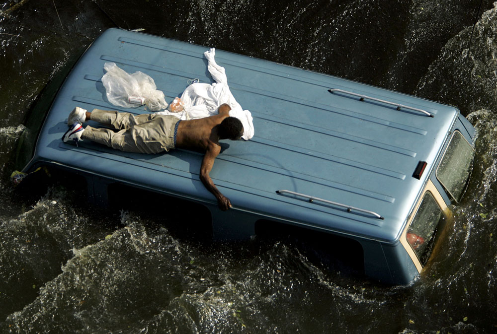 Click to view full size File photo of a man clinging to the top of a vehicle in the aftermath of Hurricane Katrina in New Orleans