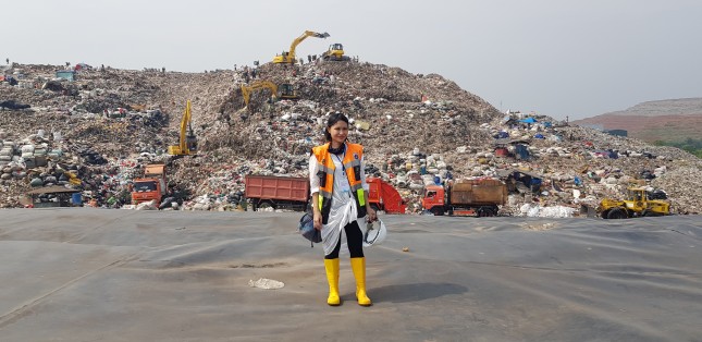 Tiza standing in front of a dumping site