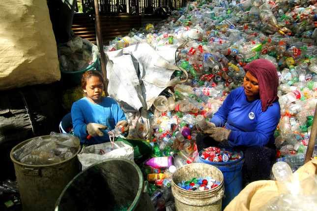 ANGONO, RIZAL, PHILIPPINES - JULY 4 2018: Workers of a materials recovery facility sort through plastic waste and segregate them for proper recycling.