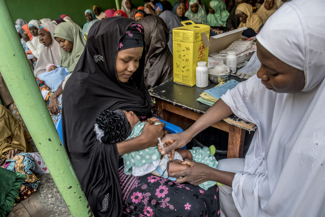 In Sokoto to see the Immunization program sponsored by JSI and MCSP as well as local partners. Local hospital WCWH, Women and Children Welfare Hospital, where lots of women bringing their children to be vaccinated.  The senior community health worker (in yellow and wearing glasses) is Fasilat Mohammed, CDC NSTOP person. The young women in white are student health workers and those in yellow are health workers.    This hospital is in Ward Sarkinmusulmi. Children were given three vaccines, Polio, BCG (TB) and PENTA VALENT which has five vaccines in it. Shown:  Rukayya Aboulkadia, wearing white but doing the vaccinations is the RI Service provider.  Since it's a centralized hospital people are coming in from all over Sokoto. Giving a vaccination.