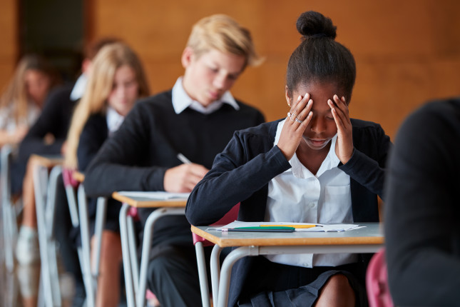 Anxious,Teenage,Student,Sitting,Examination,In,School,Hall